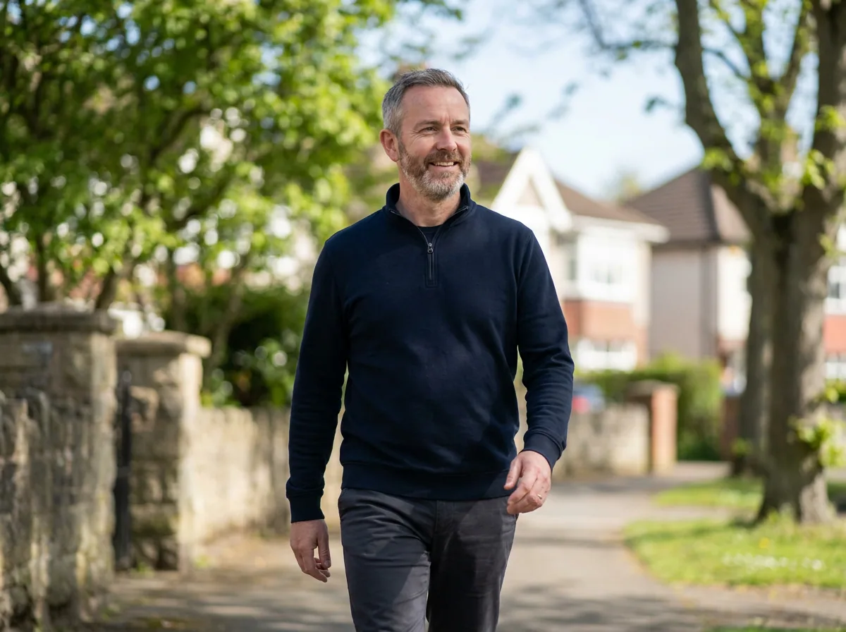A man walking easily along a tree lined street in the morning